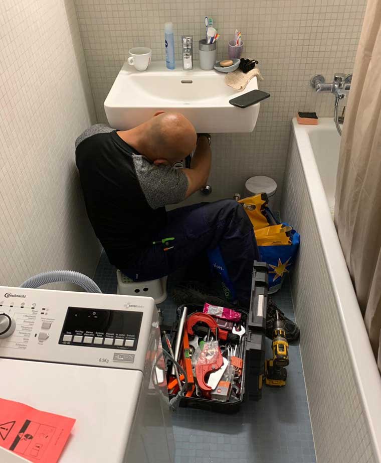 plombier en train de réparer un lavabo dans une salle de bain